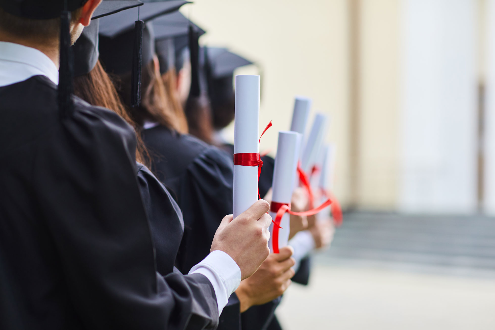 A group of diploma programme graduates holding their scrolls